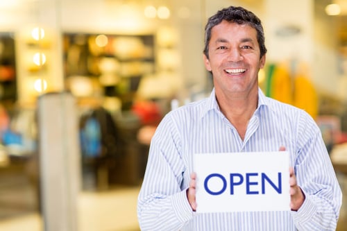 Male franchise owner holding an open sign and smiling