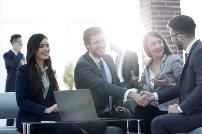 Two men and two women at a business meeting using sales enablement technology with the sun in the background